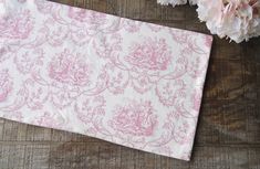 pink and white fabric with flowers on wooden table next to it's edge,