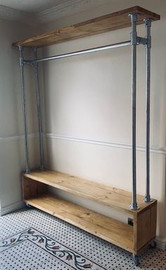 a wooden bench sitting in the middle of a room next to a wall with metal pipes on it