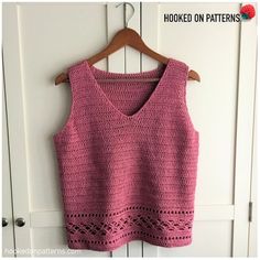 a pink crocheted top hanging on a white door with the words hooked on patterns written below it