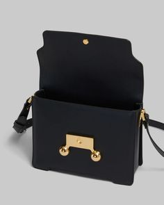 FINAL SALE The Black Leather Trunkaroo Medium Shoulder Bag by Marni is a rectangular shoulder bag featuring a front flap with magnetic closure and engraved Marni lettering, contoured base, and oversized stud detail. Detachable and adjustable buckled shoulder strap: can also be worn as a clutch. Made in Italy Body: 100% Calf Leather - Lining: 100% Ovine Leather - Metallic Parts: 100% Brass - Metallic Parts: 100% Steel SBMP0195U0P694800N99 Modern Rectangular Flap Bag With Branded Hardware, Rectangular Saddle Bag With Magnetic Closure, Modern Satchel With Branded Hardware And Flap, Modern Rectangular Saddle Bag With Branded Hardware, Designer Rectangular Flap Bag With Metal Hardware, Rectangular Flap Bag With Metal Hardware For Work, Rectangular Workwear Flap Bag With Metal Hardware, Designer Rectangular Saddle Bag For Work, Boot Pumps