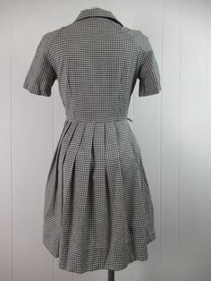 "Vintage 1950s sundress, dress. Made of black and white gingham check cotton. Has a shirt collar, button front and side zipper. Belt lops, but no belt. Made by Markstan, Schoolmaid. About a size small. Actual measurements are: 35\" around the bust line 27\" around the waist large hips 15\" shoulder seam to shoulder seam 9.5\" shoulder seam to cuff 35\" overall length In excellent condition with a 1\" seam separation(photo)." Collared Cotton Plaid Dress, 1950s Style Gingham Cotton Dress, Retro Fitted Gingham Plaid Dress, Fitted Retro Gingham Plaid Dress, Retro Cotton Plaid Dress For Picnic, Vintage Gingham Plaid Knee-length Dress, Retro Gingham Plaid Cotton Dress, Vintage Plaid Workwear Dress, Knee-length Cotton Plaid Dress For Daywear