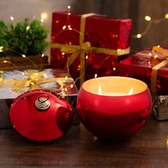 a red candle sitting on top of a wooden table next to christmas decorations and presents