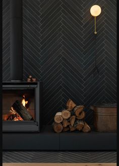 a fire place with logs in front of it and a lamp on the wall next to it