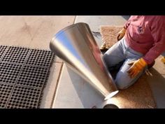 a person sitting on the ground next to a metal cone