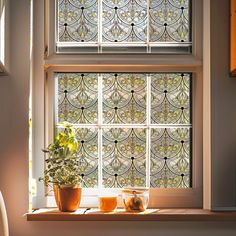 two potted plants sit on a window sill in front of a stained glass window