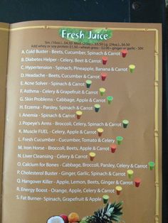 the menu for fresh juice is displayed in front of an orange and pineapple sign