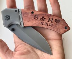 a hand holding a knife with the initials and date engraved on it's blade