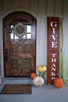 two pumpkins sitting in front of a door with the words give thanks on it