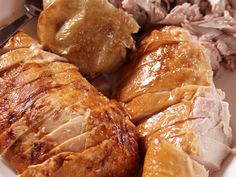 close up of meats and vegetables on a plate with utensils in the background