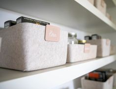 several bins are lined up on the shelves in a room with white shelving