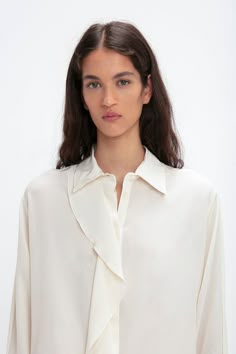 A single asymmetric drape detail cascades down the front of this silk blouse for a fluid silhouette that is enhanced by voluminous sleeves finished with buttoned cuffs. A concealed button-front closure maintains the elegant aesthetic, while the milky shade of Ivory has a nostalgic, romantic appeal. Styled with the Reverse Front Trouser Victoria Beckham Asymmetric Ruffle Blouse In Ivory  - Size 8 UK Runway Top, Winter Jasmine, Voluminous Sleeves, Elegant Aesthetic, Smocked Top, By Malene Birger, Minimal Style, Thom Browne, Blouse Styles