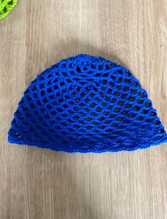 a blue crochet hat sitting on top of a wooden table