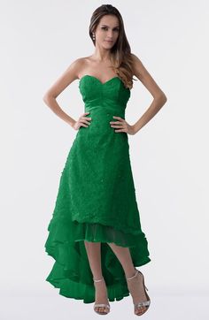 a woman in a green dress posing for the camera with her hands on her hips