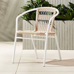 a wicker chair sitting in front of a plant