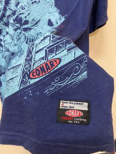 a blue shirt with an image of a train on it and some other things in the background