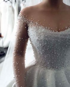 a woman in a wedding dress with pearls on it