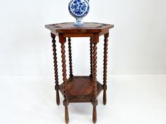 a wooden table with a blue and white vase sitting on it's side stand