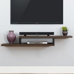 a flat screen tv sitting on top of a wooden shelf next to a vase and potted plant