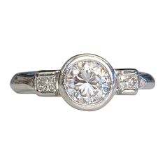 Details: Modern vintage with a sweet heart carved into the side of this Mid-Century 1940's Platinum Diamond ring. This ring has a round brilliant cut measuring .83cts, with a combined total weight of just under one carat—.98 carats. A classic, and timeless style, full of sparkle and flare this ring would make a perfect engagement ring. This ring comes with an appraisal. Please ask all necessary questions prior to placing an order. Appraisal reads: Platinum diamond ring. Bezel set in the center i Classic Bezel-set Round Diamond Ring, Classic Round Diamond Ring With Bezel Setting, Classic Diamond Ring With Bezel Setting, Classic Diamond White Diamond Ring With Bezel Setting, Classic Diamond White Ring With Bezel Setting, Classic Bezel Set Diamond Promise Ring, Classic Bezel Set Cluster Promise Ring, Classic Round Cluster Ring With Vvs Clarity, Gia Certified Art Deco Rings