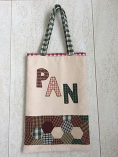 a tote bag with the word pan on it hanging up against a white wall