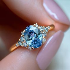 a woman's hand holding a blue and white diamond ring