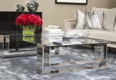 a living room with a couch, coffee table and flowers in a vase on the floor