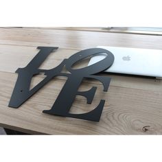 an apple laptop computer sitting on top of a wooden table next to the letter e