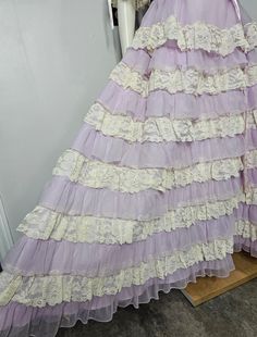 Vintage 1970s Southern Belle style dress. Lavender and off white. Lace trimmed scoop neck with sheer puff sleeves. Fitted bodice and waist. Sweeping tiered ruffle lace and sheer nylon bottom. Fully lined. Back zip closure. Great condition. No rips, holes, or stains noted. Elastic on sleeve cuffs and neckline is loose, but still wearable. The maker is Dance Allure.  No size tag, so please double check measurements below as there are no refunds or exchanges. Measurements: Bust, 36" Waist, 27 Hip, Southern Belle Style, Dress Lavender, Purple Lavender, Lace Maxi, Southern Belle, Lace Maxi Dress, Fitted Bodice, Vintage 1970s, Style Dress