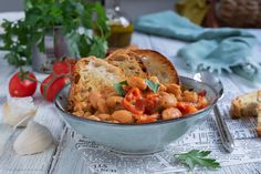 a bowl filled with beans and vegetables next to bread