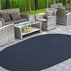 an outdoor area with wicker furniture and a red rug