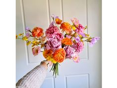 a person holding a bouquet of flowers in front of a white door with wooden paneling