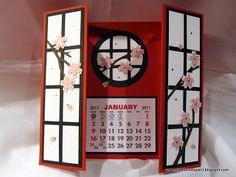 a red and white calendar with cherry blossoms on the front, in an open window frame