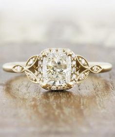 an old - fashioned diamond engagement ring sits on a wooden surface