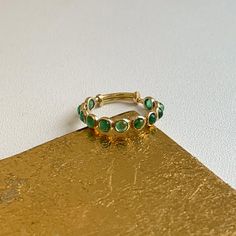 18KT yellow gold ring with round, genuine, bezel-set, emeralds band ring. Great for stacking, wedding band, anniversary, birthstone etc... Totally adjustable to wear on different size fingers! Weight: 1.2 grams Adjustable sizing bar in back, but we can also do up in any size and with other gemstones. (11) Genuine, round, cabochon emeralds measures: 3mm Bezel-set emerald 1.82 carat emeralds Stamped 18K Adjustable Gold Stackable Emerald Ring, Adjustable Stackable Gold Emerald Ring, Stackable Emerald Rings With Round Shape, Emerald Open Ring With Bezel Setting, Yellow Gold Emerald Stackable Rings, Open Emerald Ring With Bezel Setting For May Birthstone, Adjustable Yellow Gold Emerald Ring, Gold Stackable Emerald Ring, Gold Stackable Rings With Emeralds