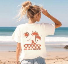 "Design features a scene of palm trees and surf boards at the beach, with sun and seagulls overhead. Below is a checkered stripe, and below that is text \"Find me at the beach\" in a retro bubble font.  Comfort Colors Unisex Tee Info ∙ 100% ring-spun cotton ∙ Medium fabric (6.1 oz/yd² (206.8 g/m ∙ Relaxed fit, and can be sized up for a looser fit ∙ Sewn-in twill label ∙ Designs are Direct to Garment printed, resulting in a soft texture ∙ Please note color shades maybe slightly different to the p Palm Tree Tshirt Design, Surf Crush Aesthetic Outfits, Summer Tops With Palm Tree Print For Surfing, Retro T Shirt Designs, Beach Shirt Design, Find Me, Surf T Shirts, Bubble Font, Coconut Girl Aesthetic