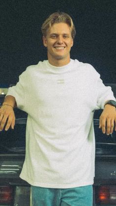 a man standing in front of a car with his arms out