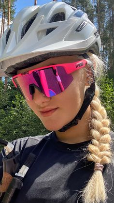 a woman wearing a helmet and goggles on her face with trees in the background