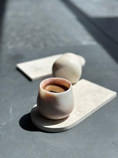 two white and brown bowls sitting on top of a gray table next to each other