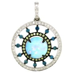 Elegance and enchantment converge in this beautifully crafted pendant, a true masterpiece in 18k white gold weighing 9.82 grams. At the heart of this exquisite piece lies a mesmerizing 5.47-carat round opal, captivating with its play of colors and natural brilliance. Surrounding the opal are stunning round canary diamonds, set in black rhodium, adding a striking contrast and enhancing the opal's vibrant hues. The next layer features 12 brilliant blue round diamonds, totaling 0.74 carats, which add a touch of serene elegance. Completing the design, an outline of dazzling white round diamonds perfectly frames the entire piece. The combined weight of the white and canary diamonds is 1.2 carats, contributing to the pendant's overall sparkle and sophistication. This pendant is a harmonious blen Canary Diamond, Purple Jewelry, Black Rhodium, Opal Pendants, Round Diamonds, Jewelry Necklace Pendant, Jewelry Collection, Opal, Jewelry Necklaces