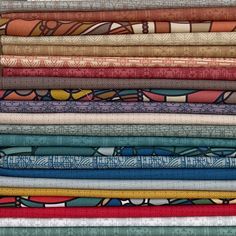 an assortment of colorful fabrics stacked on top of each other in different sizes and colors