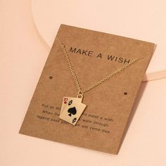 a card necklace with the words make a wish written on it and a gold chain