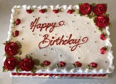 a birthday cake with white frosting and red roses