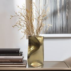 there is a vase with some plants in it on the table next to three books