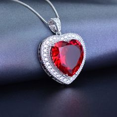 ✨ Unveil the Brilliance of Love with Our Moissanite Heart Pendant, a Masterpiece of Italian Craftsmanship and Stellar Beauty. ✨ Why This Moissanite Pendant is Your Heart's Desire: Precision-Cut Elegance: The heart-shaped centrepiece, meticulously crafted with a 16x16mm Ruby cut Healing zircon, captures the essence of pure love. Its exquisite cut reflects a symphony of light, promising to keep the flame of your affection ever-luminous. Diamond-Cut Italian Chain: Accompanying this stunning pendant is a high-quality sterling silver chain, fashioned with diamond-cut moon shape cuts. These intricate details catch the light, creating an unparalleled sparkle reminiscent of a star-studded night sky. Rhodium Plated for Perfection: Clad in rhodium plating, this necklace offers the prestigious look a Perhiasan Aesthetic, Ruby Heart Necklace, Beautiful Pendants, Necklace Ruby, Ruby Heart, Chicano Art, Garnet Pendant, Ruby Necklace, Necklace Heart