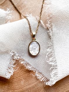 Mother of Pearl Immaculate Conception Necklace Rich with symbolism, this Mother of Pearl Necklace features the Blessed Mother surrounded by a gold plated frame, suspended from a 16” gold filled rope chain. Gold Oval Pendant Necklace For Wedding, Keepsake Gold Necklace With Delicate Chain, Gold Necklaces With Delicate Chain For Keepsake, Gold Necklace With Delicate Chain For Keepsake, Elegant Miraculous Medal Necklace, Elegant Oval Necklace With Miraculous Medal, Oval Gold Necklace For Keepsake, 14k Gold Filled Oval Pendant Necklace For Gift, Elegant Miraculous Medal Jewelry For Gift