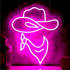 a neon sign with a cowboy hat on it in front of a purple wall and a bottle