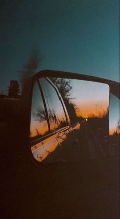 the rear view mirror of a car with trees reflected in it