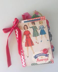 a book with a red ribbon tied around it on top of a white table next to an ornament