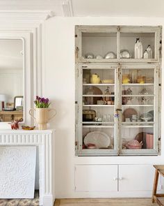 an old china cabinet in the corner of a room with white walls and wood floors