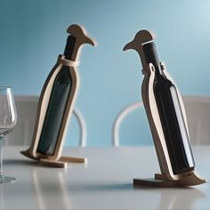 two wine bottles are shaped like penguins on a table next to a glass and bottle opener